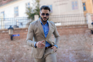 sexy unshaved man with sunglasses walking with hand in pocket