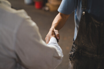 Mechanic technician man shaking hands with customer after finish checking the car at the garage, two people handshake for a working job at professional auto car repair service center