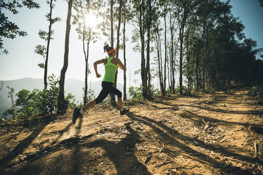 Woman trail runner running at tropical forest mountain peak
