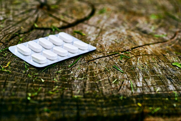 White pills in blister pack on a wood stump background