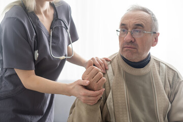 Portrait of mature female psychiatrist interviewing handicapped senior man during therapy session,...