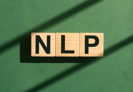 Neuro-linguistic programming, NLP acronym on wooden cubes blocks on green background