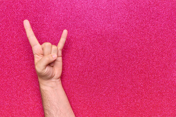 bottom hand gesture horns rock and roll skateboarding with 2 fingers on pink background with glitter