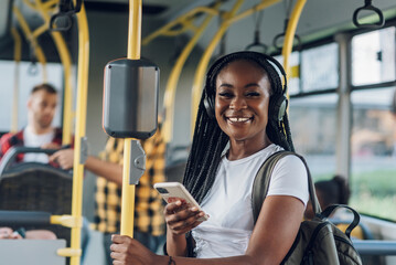 African american woman riding in a bus and using a smartphone and headphones