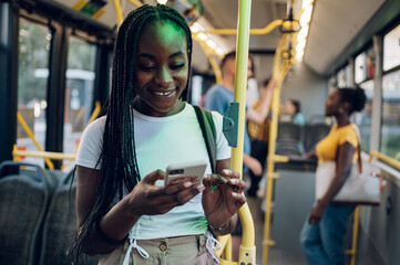 African american woman riding in a bus and using a smartphone