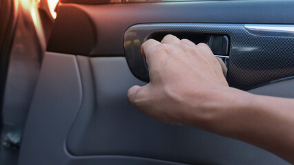 Passenger's hand holds the door to the side of the car from the inside. Interior uses gray tones mixed with cream.