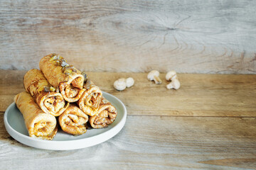 English-style Crepes with mushrooms,traditional homemade filling stuffed for thin savory pancakes,blini with cabbage,chicken,cheese,onions close-up on wooden table,selective focus.Maslenitsa food menu