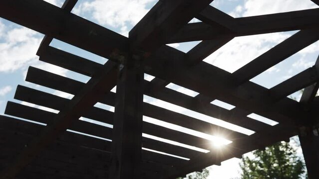 Wooden pergola in a city recreation park with a lake in the residential area