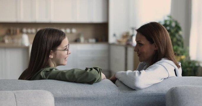 Middle aged mom and daughter talk sit on sofa. Happy two generations of women engaged in trustworthy conversation, enjoy confidential friendly dialogue. Good relationship, understanding, wise advice