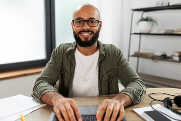 Excited latin man in eyeglasses typing on laptop computer keyboard and looking at screen, pov shot