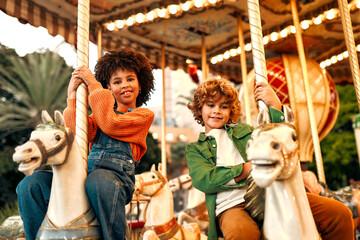 Kids having fun on a carnival Carousel - obrazy, fototapety, plakaty