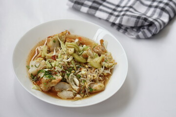 Kupat tahu is a traditional Indonesian food consisting of ketupat and tofu in peanut sauce. Usually include rice cake, tofu, bean sprouts, brown sugar, and prawn crackers. Served in white plate.