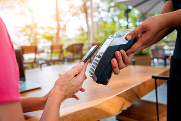 Woman using contactless payment by mobile phone with QR code at cafe
