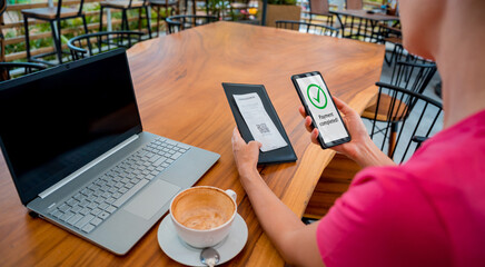 Woman using contactless payment by mobile phone with QR code at cafe