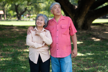 Fototapeta premium Portrait of lovely elderly couple hugging each other with love and happiness in a park outdoor. Happy smiling Elderly couple enjoying with positive emotions at garden