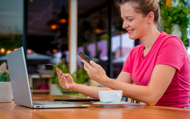 Woman using contactless payment by mobile phone with QR code at cafe
