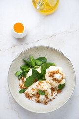 Plate with steamed cauliflower, ricotta and fresh spinach salad, above view on a light-beige marble background, vertical shot