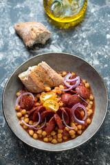 Grey bowl with chorizo and chickpea stew, vertical shot on a dark-brown granite background