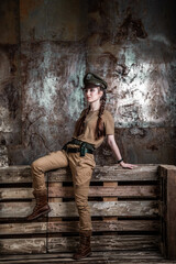 American pilot. A beautiful young woman in a uniform and with a weapon on the background of a metal wall. Staged photo. Studio light.