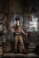 American pilot. A beautiful young woman in a uniform and with a weapon on the background of a metal wall. Staged photo. Studio light.