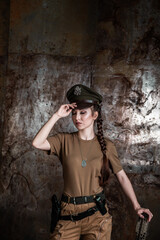 American pilot. A beautiful young woman in a uniform and with a weapon on the background of a metal wall. Staged photo. Studio light.