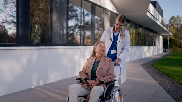 Young woman doctor taking care of senior woman at wheelchair.