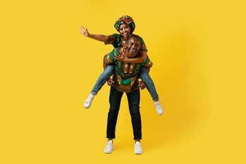 Fototapeta na wymiar Happy black couple in traditional costumes posing on yellow