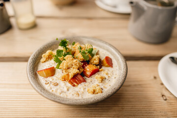 Bowl of clean healthy fruity porridge on wooden table as part of delicious breakfast brunch - obrazy, fototapety, plakaty