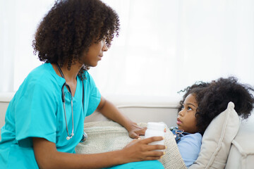 African American ethnicity female doctor and little girl in hospital, pediatrician taking to a little girl who laying down on the bed or sofa in hospital to talk about her sickness.