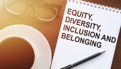 Fototapeta Equity, diversity, inclusion, belonging. Text on notebook with coffee and eyeglasses. Business, signs. obraz