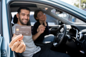 Happy smiling Caucasian couple sitting inside his new car showing credit card. Personal transportation auto purchase concept.