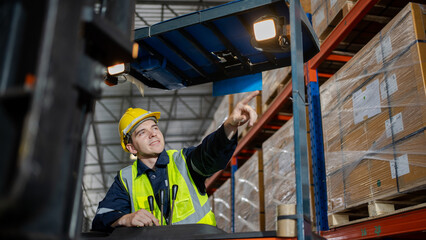 Engineer worker in a warehouse hard hat working. walking through logistics center warehouse factory construction site logistics forklift driver man. © Chalermphon