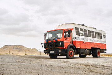 Big red and white truck on the background of mountains and clouds
