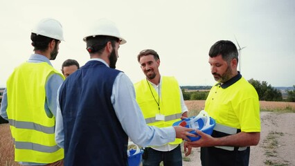 Labor safety inspector talking and giving helmets to construction workers Chief engineer distributing safety material to employees. Work risk concept. Slow motion. High quality 4k footage
