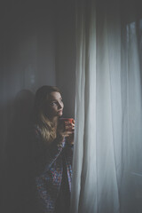 Cold, depressed, young woman at home feeling sad, lonely, anxious (color toned image)