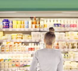 Woman choosing frozen food from a supermarket freezer, reading product information
