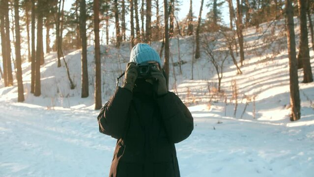 A young woman in a blue hat shoots on camera against the background of a winter landscape. High quality 4k footage