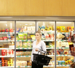 Woman choosing frozen food from a supermarket freezer, reading product information