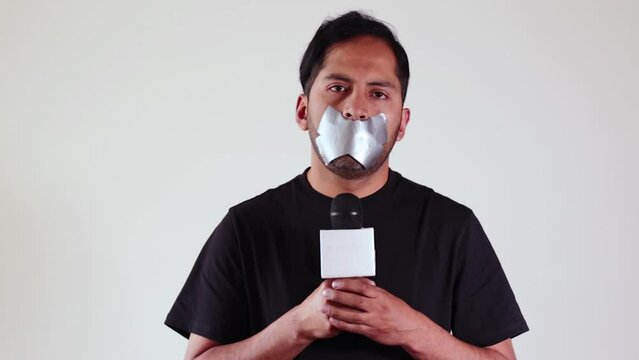 Conceptual video of Journalist with his mouth covered with tape representing censorship. Concept of journalists, media, information, media manipulation, truth.