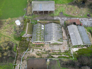 Aerial view of derelict farm buildings including hay barns and cow milking parlours. A grain silo is on the left.