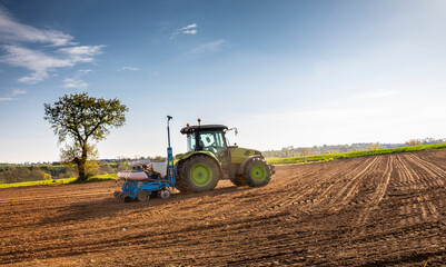 Obraz premium Agriculteur au volant de son tracteur labourant les champ au printemps.