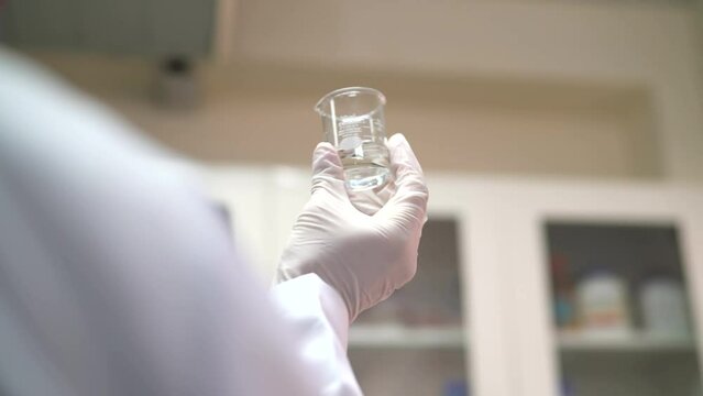 Factory worker observing small beaker in the laboratory
