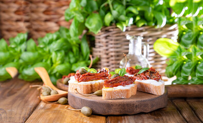 Bruschetta with sun-dried tomatoes, cheese, basil and capers. Traditional appetizer for aperitivo in Italy. High quality photo. Copy space. High quality photo