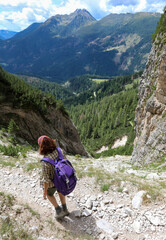 young woman walks on the trail of european alps dolomites near precipice in summer