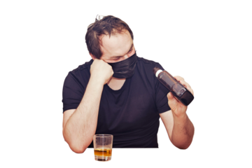 An adult man in casual clothes is sitting looking thoughtfully at a bottle of alcohol, isolated on a white background. Problems with alcoholism during the coronavirus quarantine period