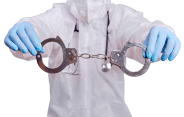 A doctor in a protective medical suit with handcuffs in his hands, isolated on a white background