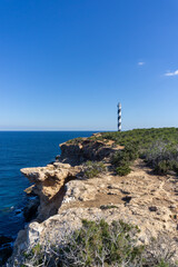Fototapeta na wymiar Portinatx lighthouse seen from the cliffs, on a sunny day, on the island of Ibiza
