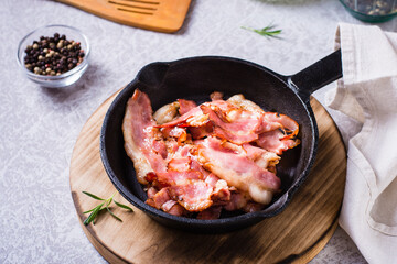 Crispy strips of bacon fried in a pan on the table.