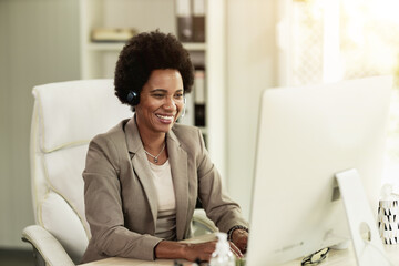 Black Woman With Headphones Working At Computer At The Office
