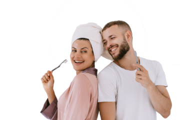 Cheerful caucasian young couple at bathroom brushing teeth toothy smiling cuddling. Newlyweds enjoying honeymoon against transparent background. hispanic girl with towel on head, fun with boyfriend.